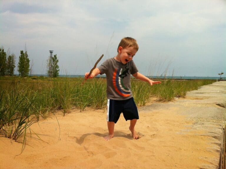 Young boy dancing in sand, color photo