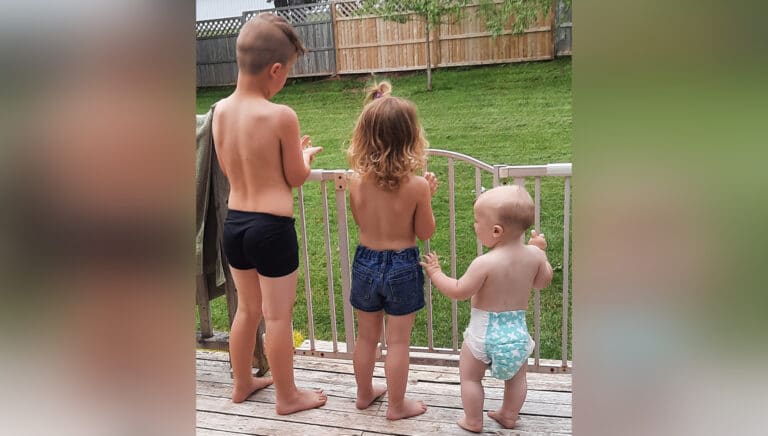 Three children with backs to camera, color photo