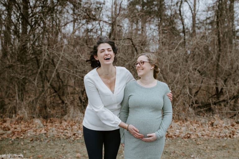Woman standing next to pregnant woman, color photo
