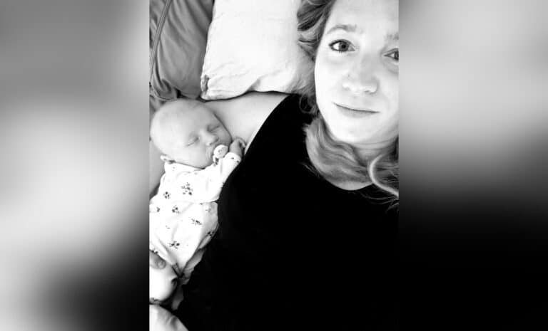 Woman lying next to infant, black-and-white photo