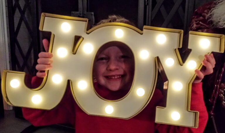 Smiling child with lighted Joy sign