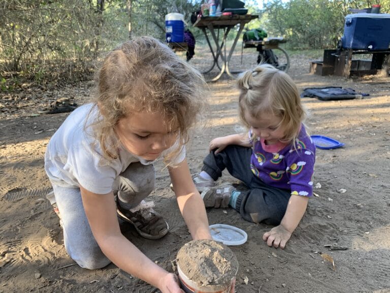 Two young children playing in the dirt, color photo