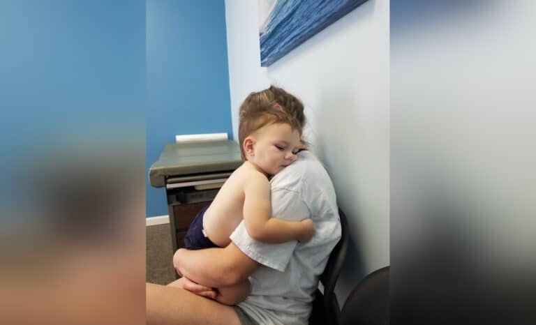 Mother holding child in doctor's exam room, color photo