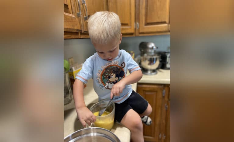 Toddler sitting on kitchen counter, color photo