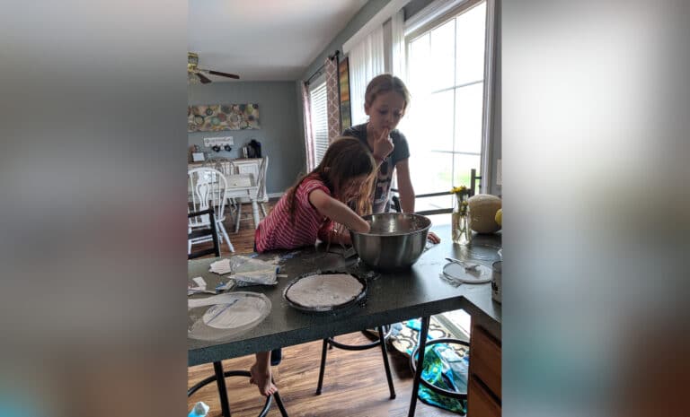 Two young girls licking from a mixing bowl, color photot