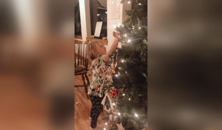 Child putting ornament on Christmas tree
