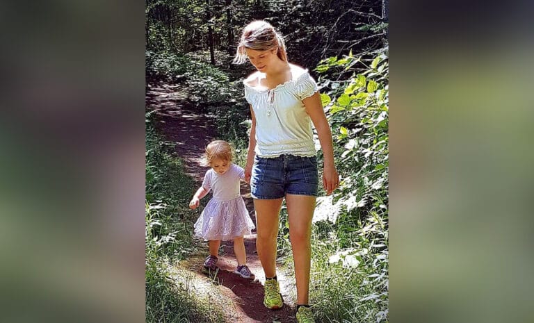 Woman and toddler walking along stream, color photo