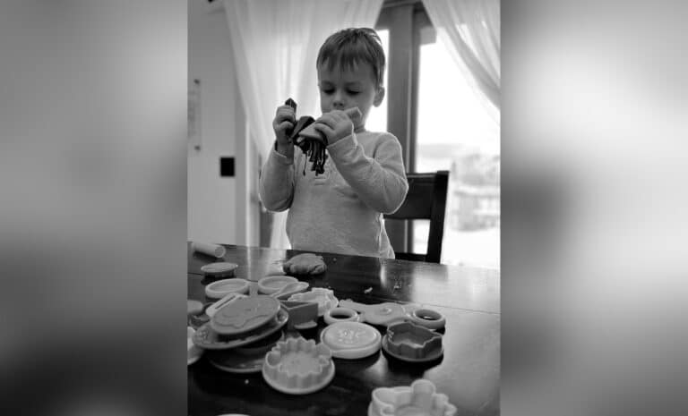 Little boy playing at kitchen table, black-and-white photo