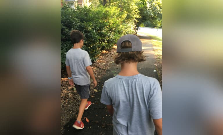 Two tween boys walking down a path, color photo