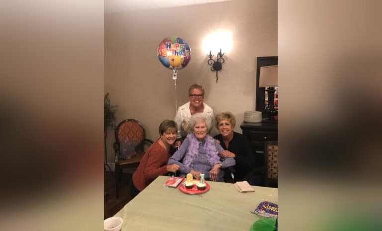 Elderly woman surrounded by grown daughters, color photo