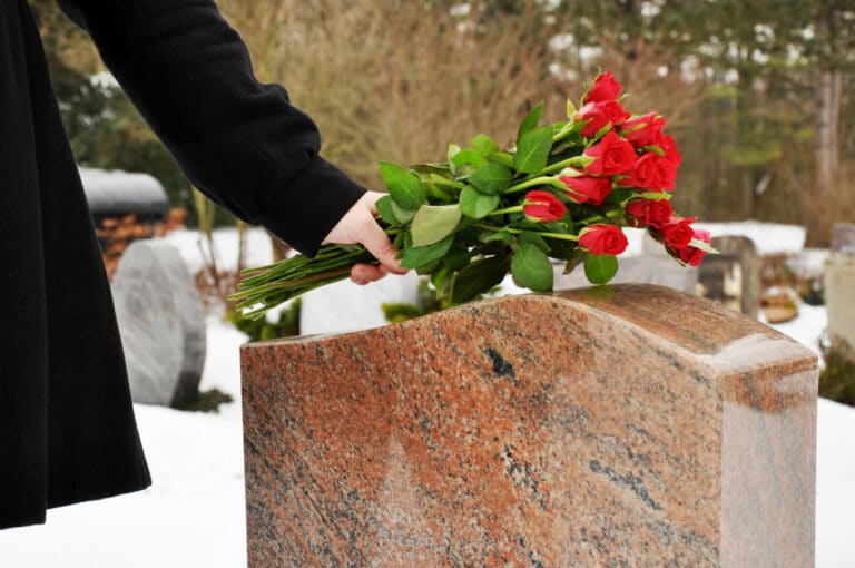Woman putting flowers on headstone