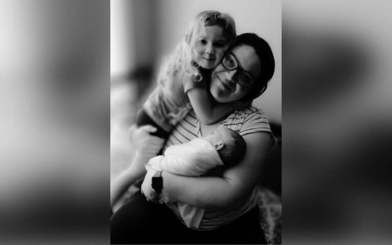Woman holding toddler and infant, black-and-white photo