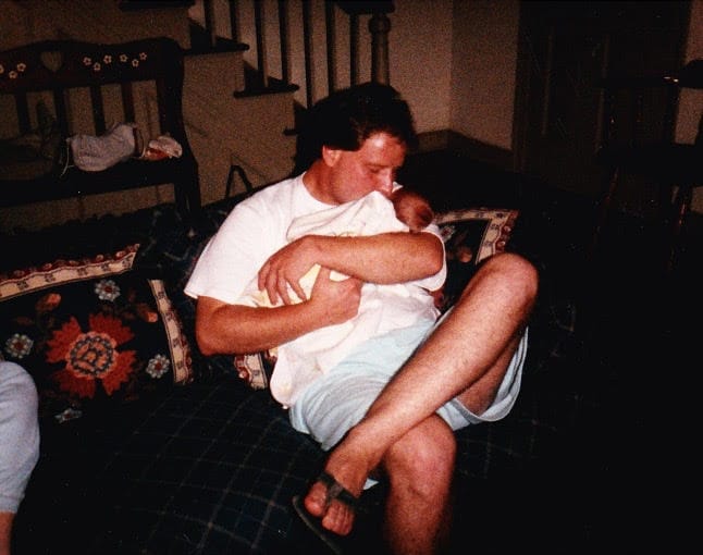 Father holding infant daughter, color photo