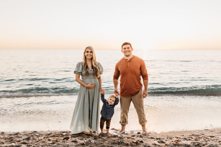 Husband, pregnant wife, and son on beach, color photo