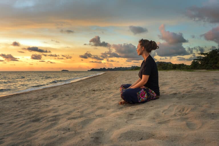 Woman sitting on beach at sunrise