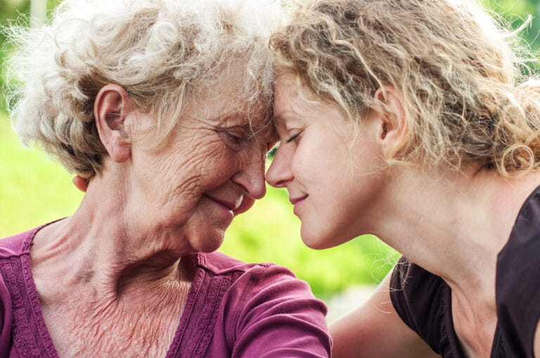 Woman and elderly mother touch foreheads