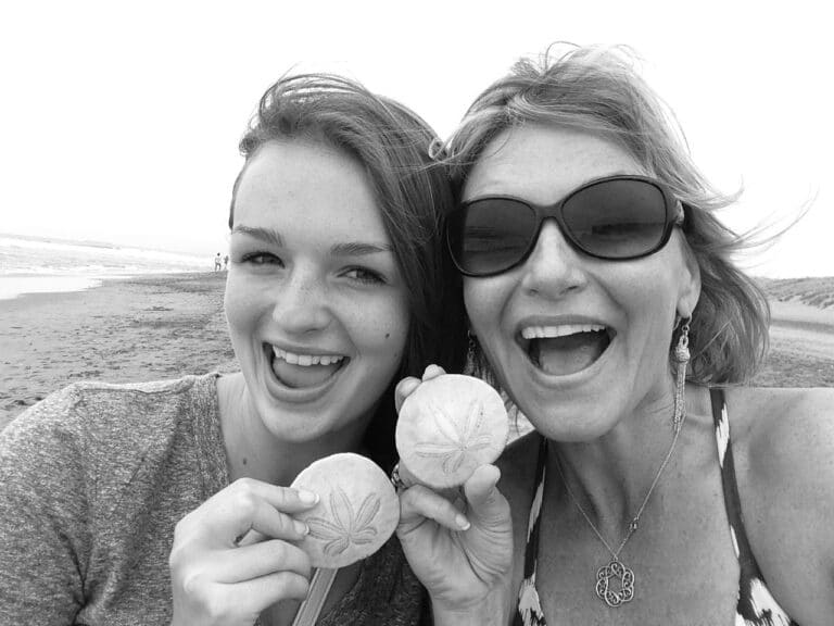 Woman and adult daughter holding sand dollars, black-and-white photo