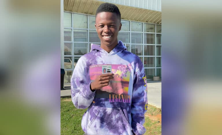 smiling high school student holds id