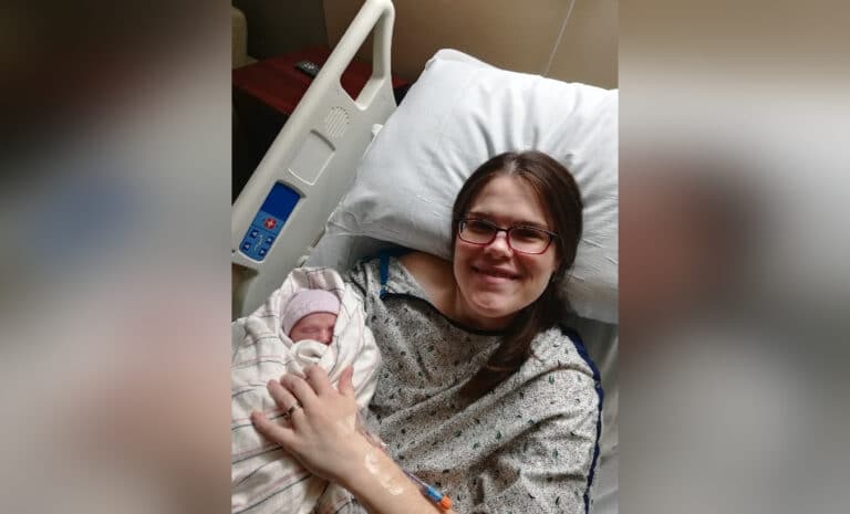 Mother holding newborn in hospital bed, color photo