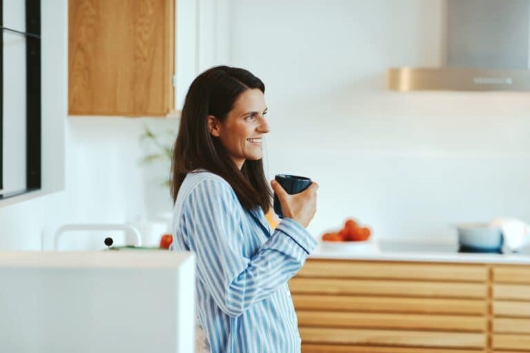 Woman holding coffee cup in kitchen