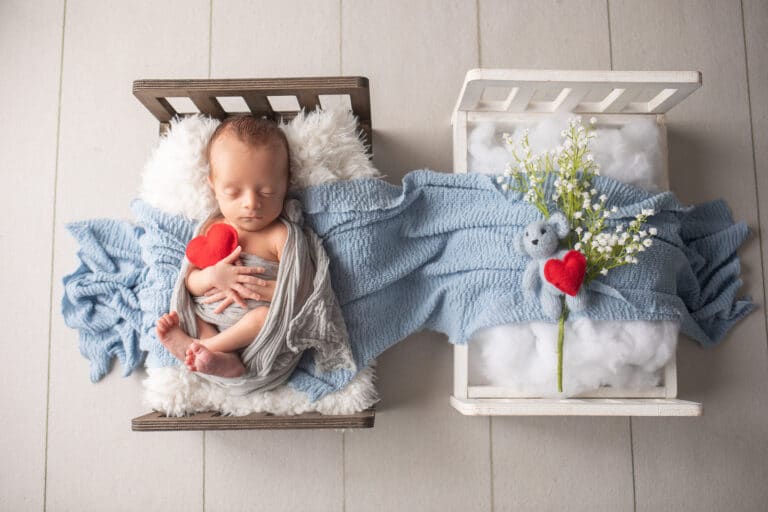 Infant lying in bed next to matching empty bed, color photo