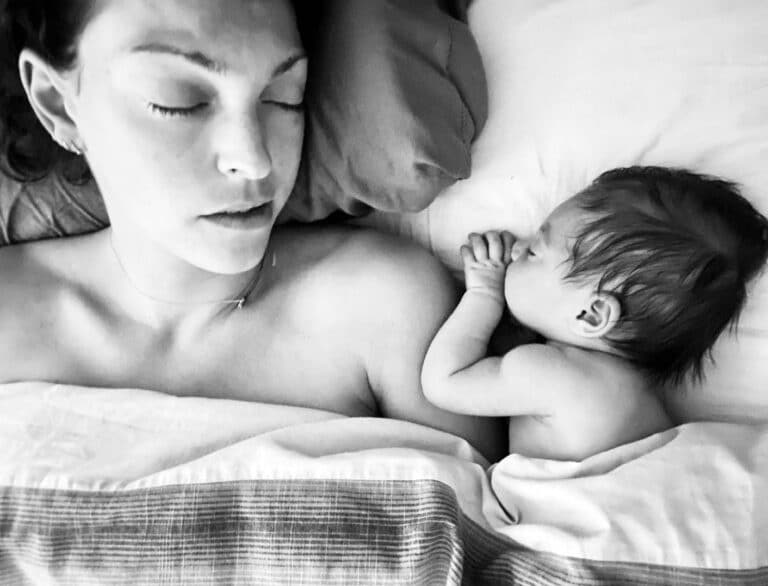Mother sleeping next to infant, black-and-white photo