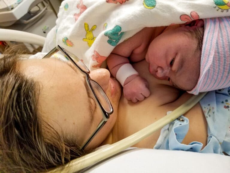 Woman holding newborn in hospital, color photo