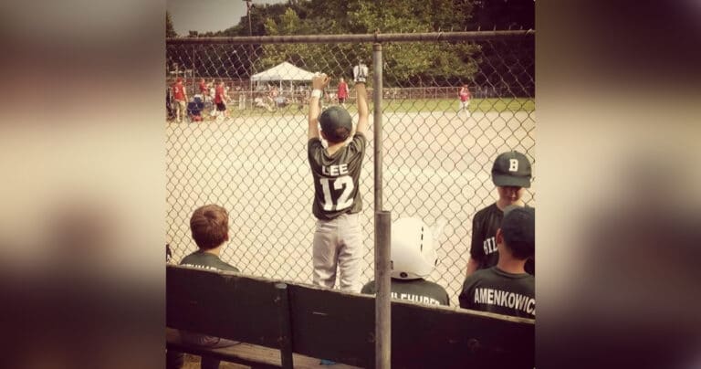 youth baseball player standing at the fence