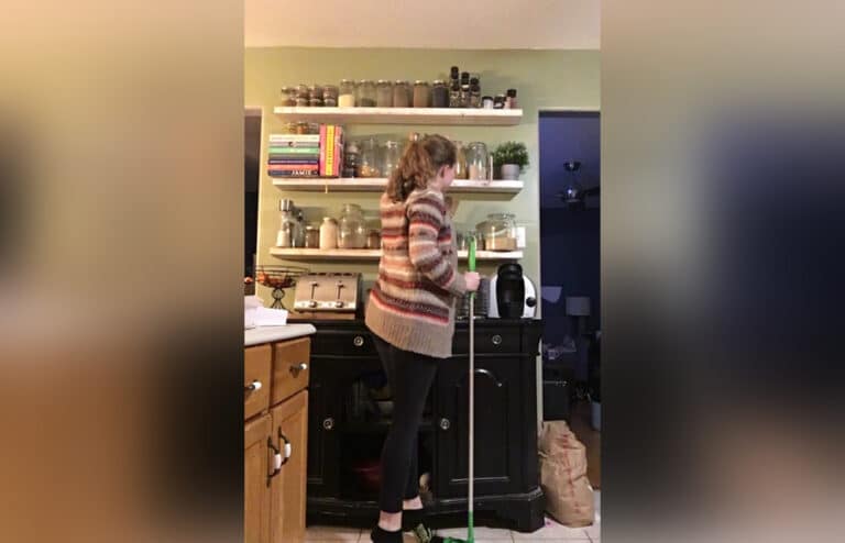 Mother standing in kitchen with Swiffer mop, color photo