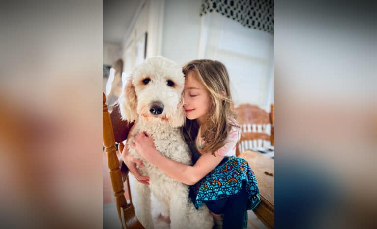 Young girl hugging dog, color photo