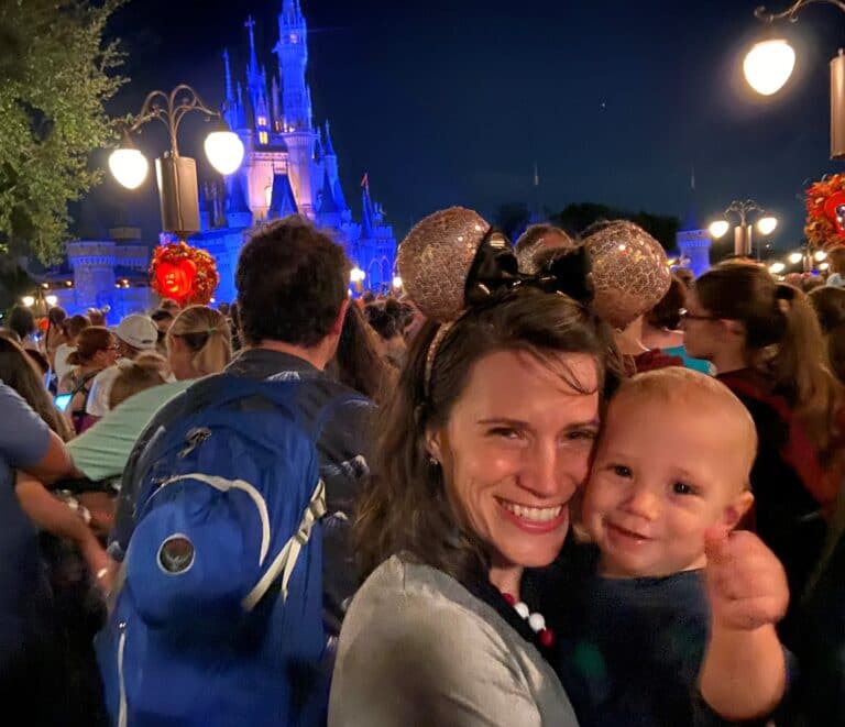 Mother and toddler smiling outside Disney castle, color photo