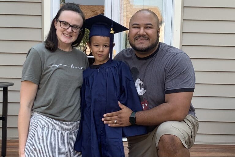 Mother, father, and little boy in graduation gown, color photo