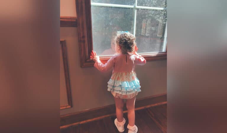 Little girl looking out window, color photo