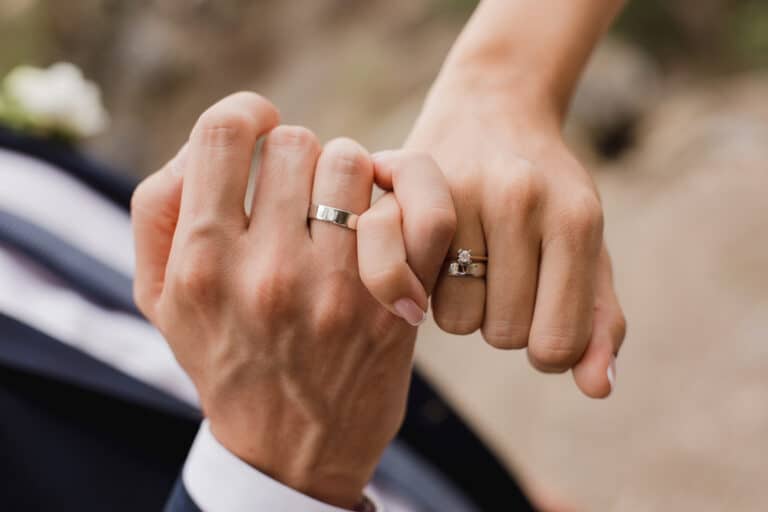 Man and woman hook fingers with wedding rings on