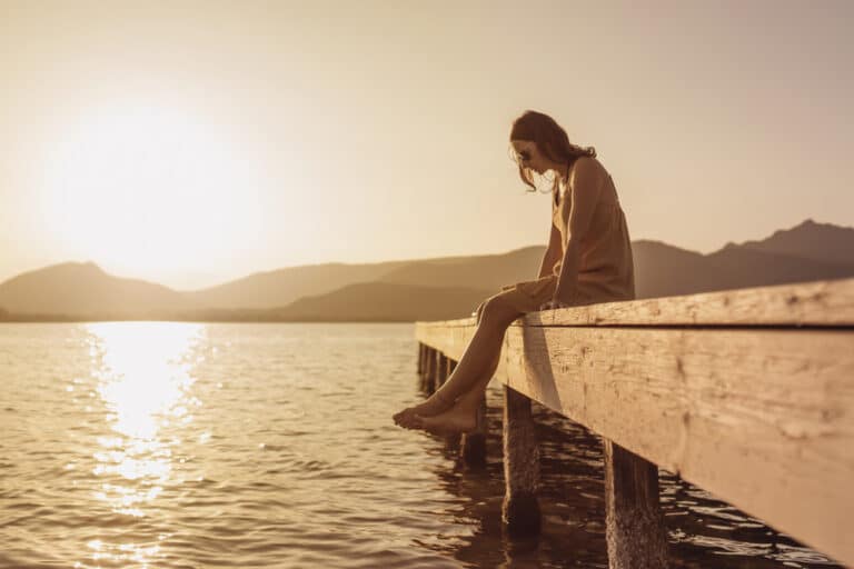 Woman sitting on dock alone by lake