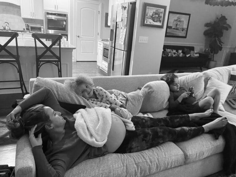 Mother lying on couch with children, black-and-white photo