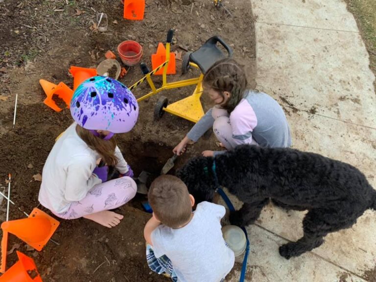 Kids digging in dirt along sidewalk, color photo