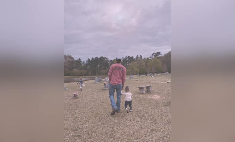 Father and toddler walking in cemetery, color photo