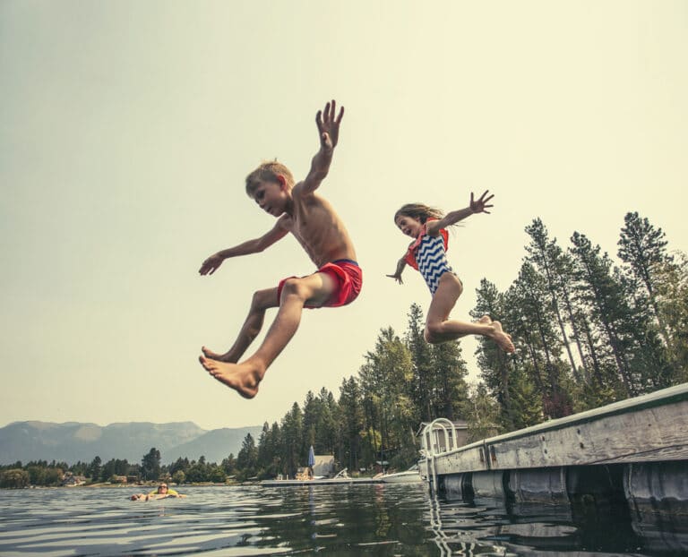 Kids jumping off dock into lake