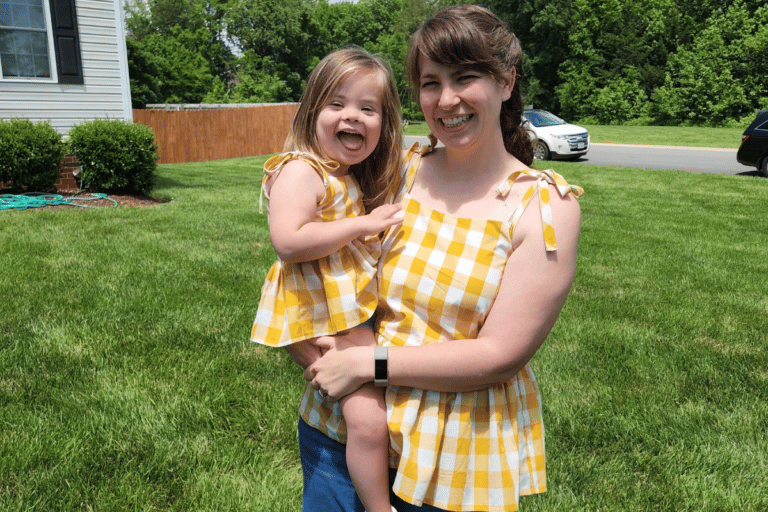 Mother holding daughter in matching shirts, color photo