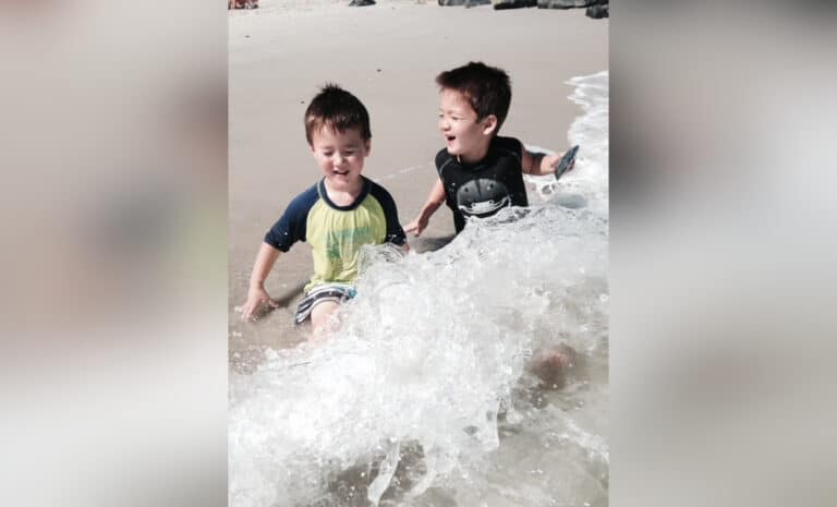 Two boys playing in the waves on the beach, color photo