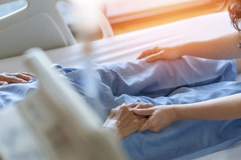 Holding hand at hospital bedside