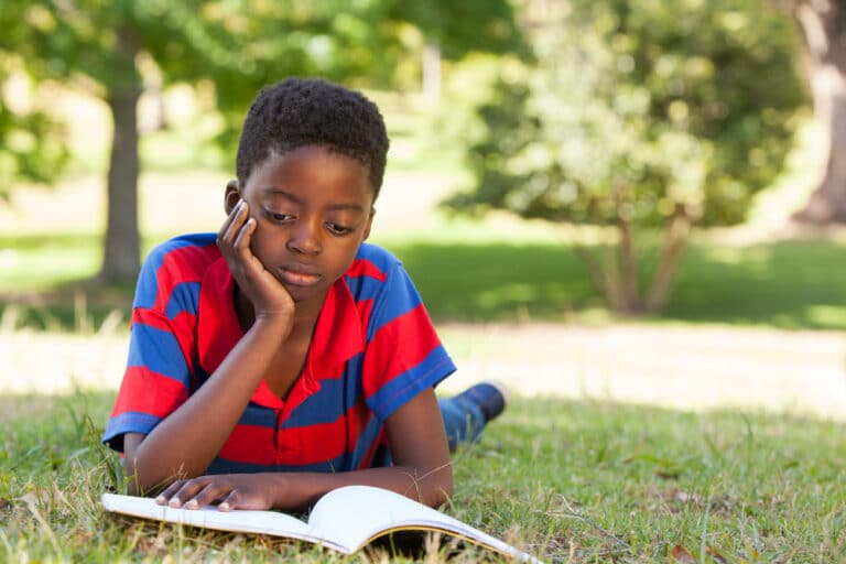 Little boy reading outside