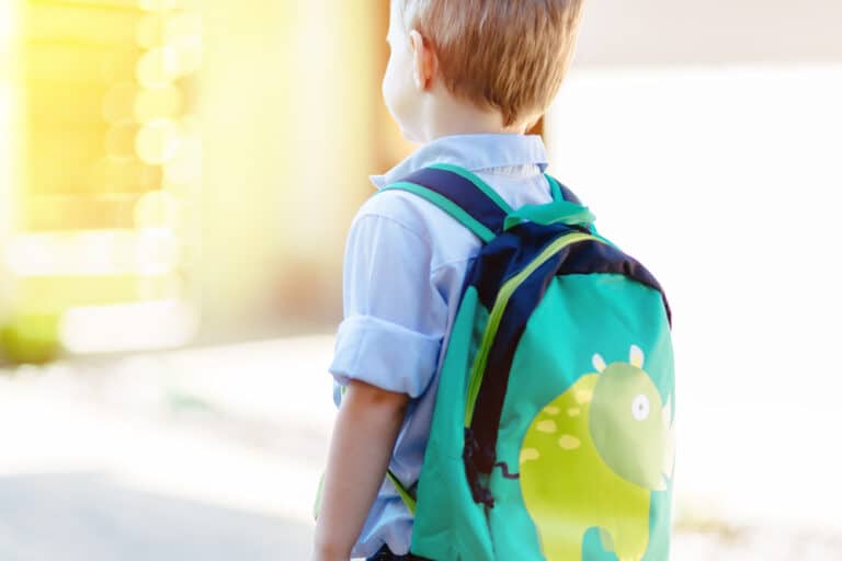 Little boy with green dinosaur backpack