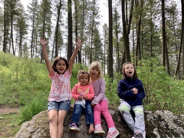 Four girls sitting on a rock in the forest, color photo