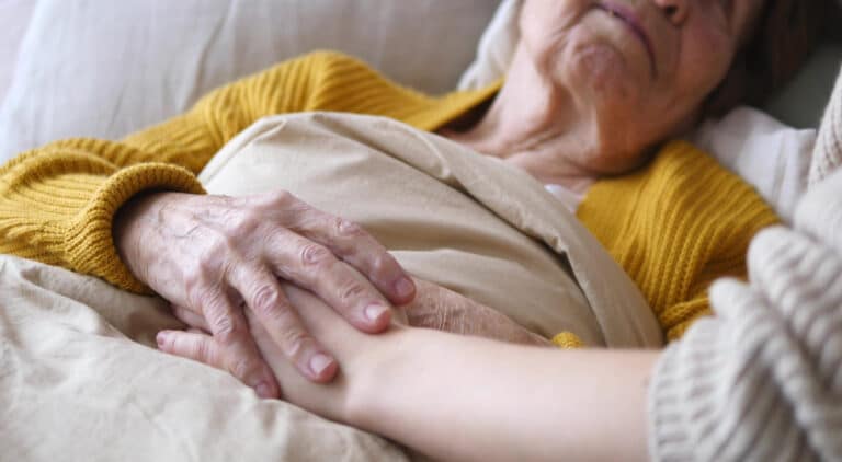 Elderly woman holding young woman's hand