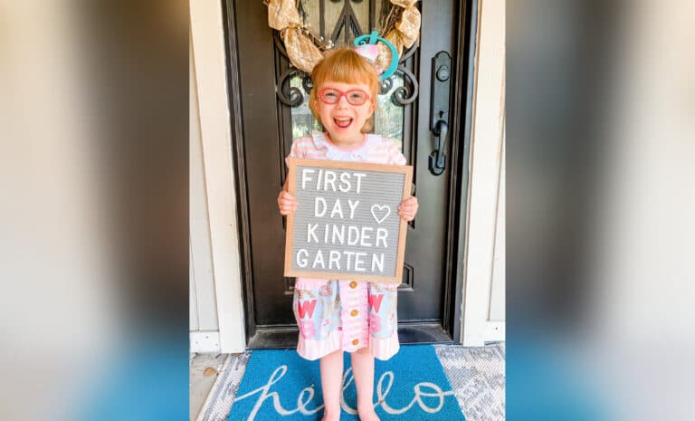 little girl holding a first day of kindergarten sign