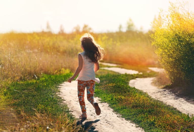 Little girl running down sunlit path