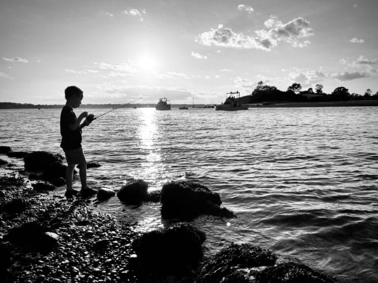 Kid standing on shore of a lake, black-and-white photo