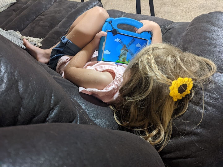 Child with tablet on couch